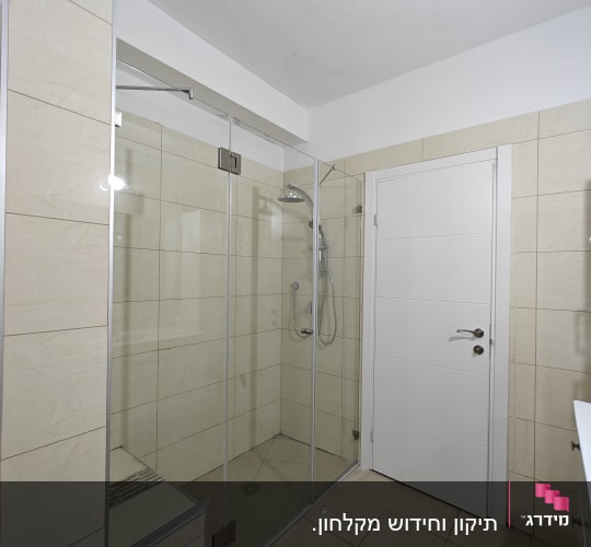 מקלחון זכוכית עם ראש מקלחת מתכתי על קיר אריחים